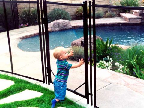 little boy in front of gate by the pool