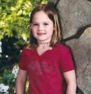 a school photo of a young girl wearing a red shirt.