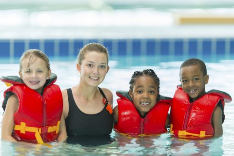 3 kids in life jacketswith swimming instructor