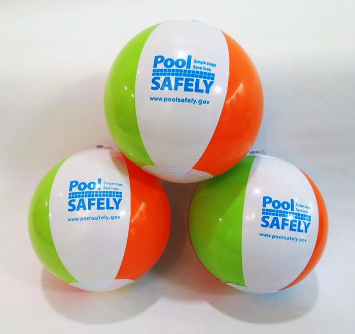 three green orange and white beach balls with the pool safely logo.