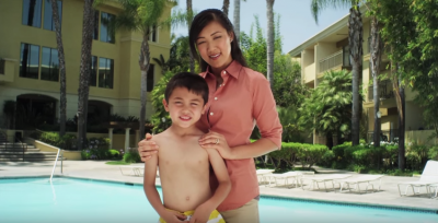 a woman and child standing next to a pool smiling.