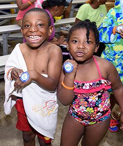 two young african-american children showing off their pledge stickers.