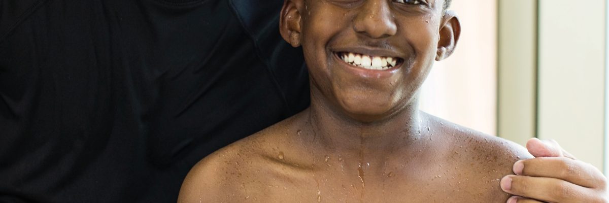 closeup of a man with his arm around a kid and both are smiling.