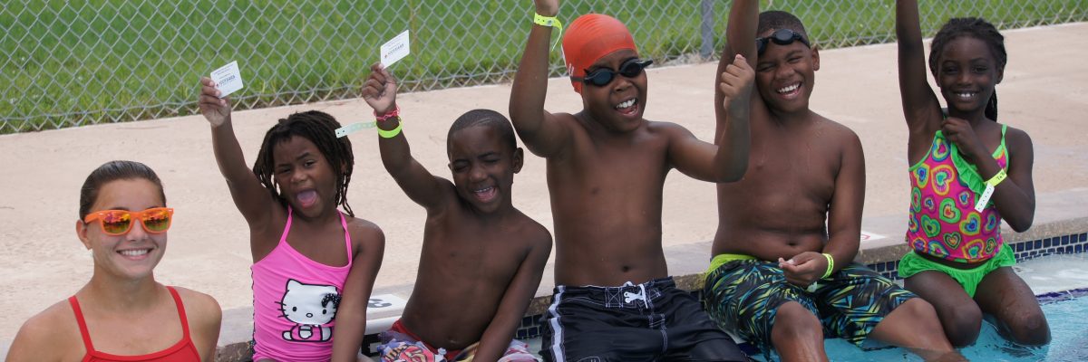 5 kids showing off thier learn-to-swim cards with the lifegaurd