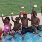 5 kids showing off thier learn-to-swim cards with the lifegaurd