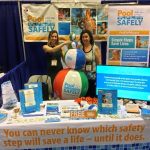 two women at a booth surrounded by pool safely materials.