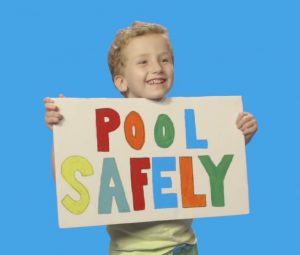 Boy holding a pool safely sign