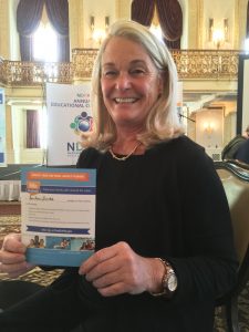 woman with light blonde hair smiling and holding her signed pledge.