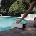 woman kneeling installing a pool alarm.