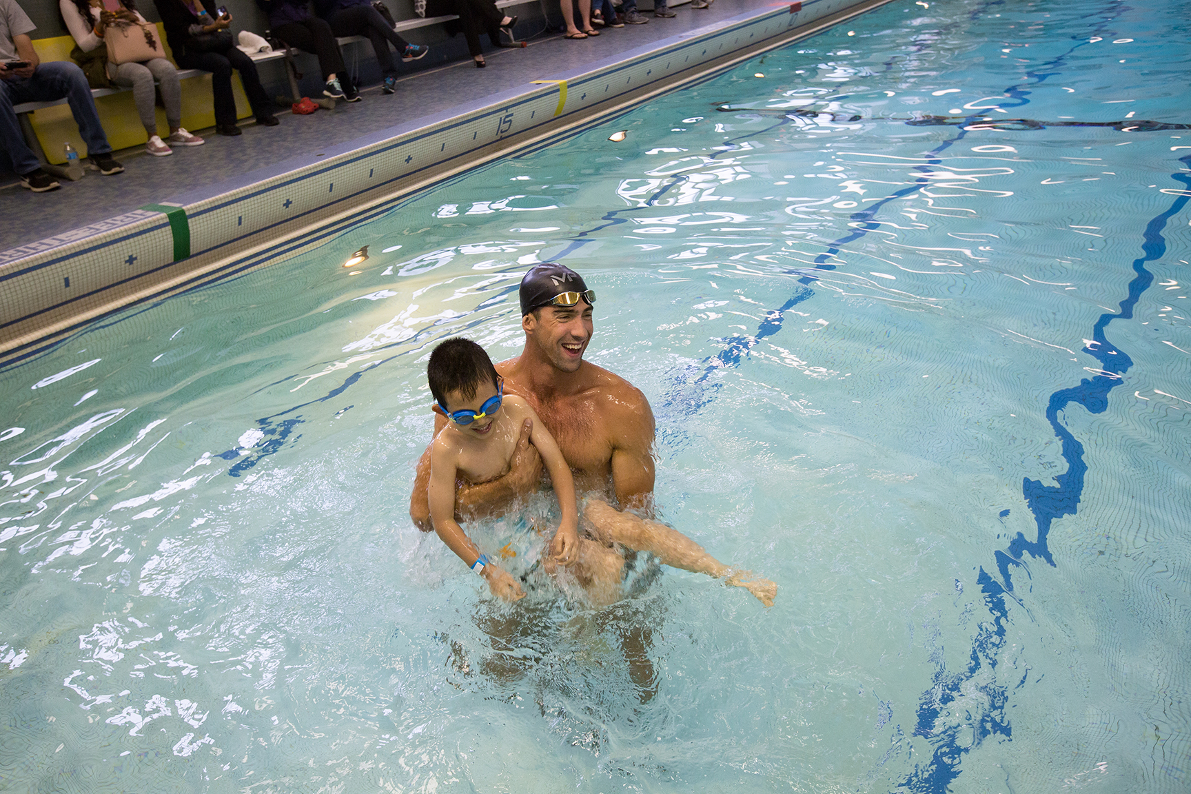 Michael Phelps in the pool holding a boy