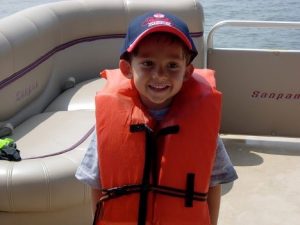 a young boy on a boat wearing a life vest.