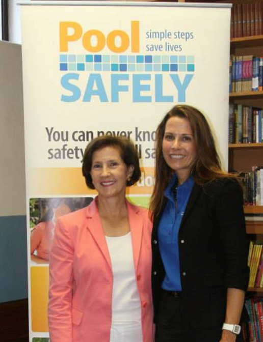 two women standing in front of a big pool safely banner.