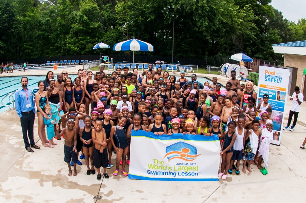 Swimming lesson participants pose for a group photo in the pool after the lesson.