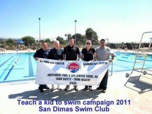 a group of 5 people holding a banner in front of a pool.