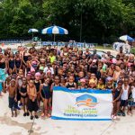 Swimming lesson participants pose for a group photo in the pool after the lesson.