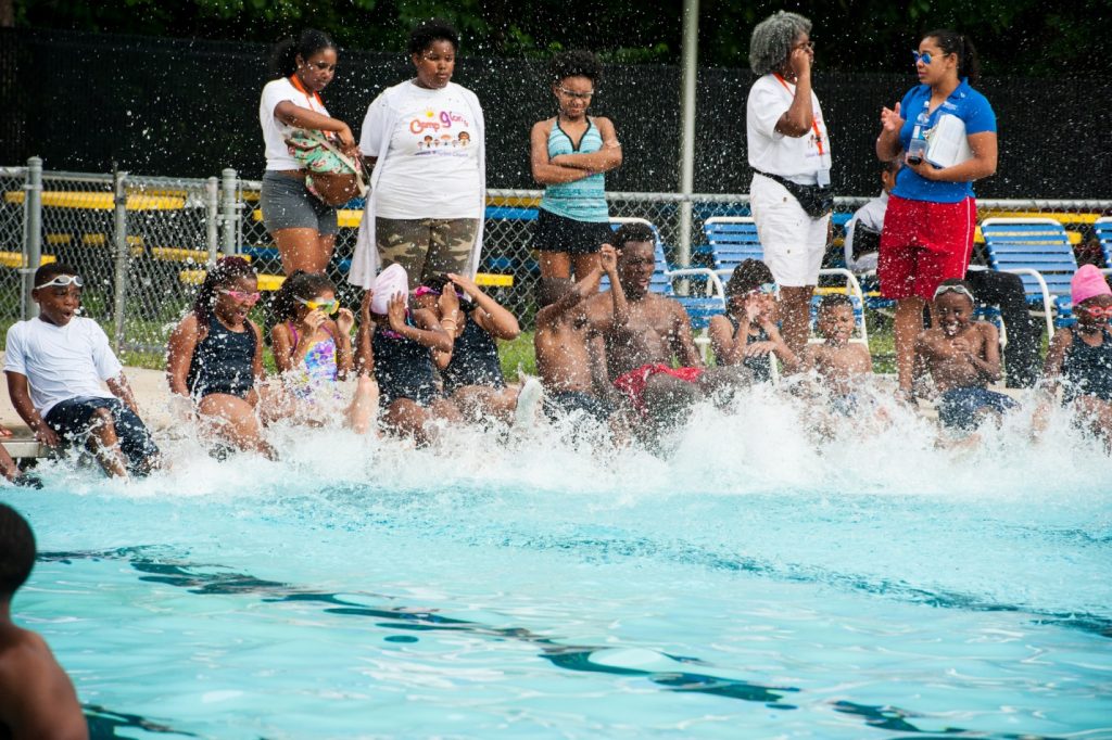 a group of children sitting on the edge of a pool splashing.