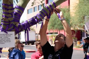 Man putting purple ribbon on a tree