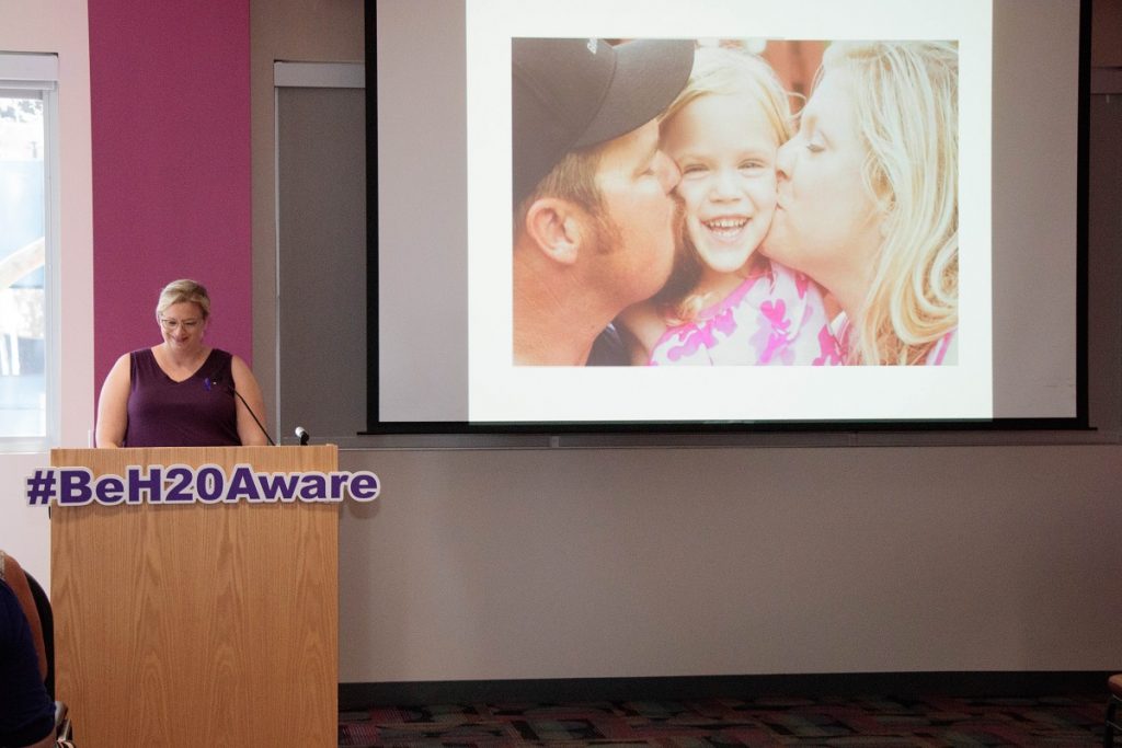 Women at podium with parents and a girl on a screen