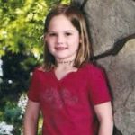 a school photo of a young girl wearing a red shirt.