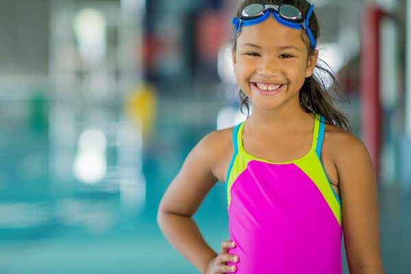 girl in pink swimsuit smiling.