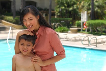 mom and son standing next to a pool