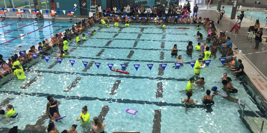 A birds eye view of a large pool with children sitting around the sides.