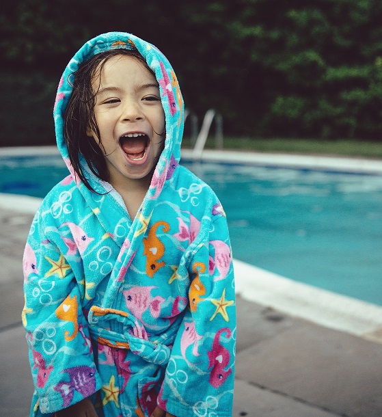 a year girl has fun posing for the camera while warming up after a good swim in the pool.