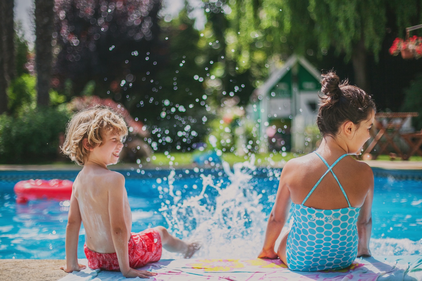 two kids having fun splashing water in poolside.