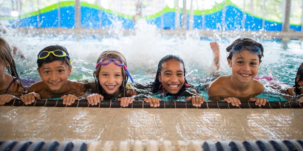 four kids in a pool holding on to the edge and kicking