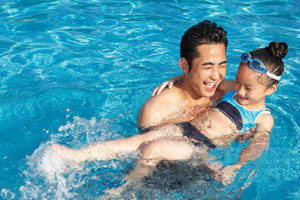 a father swimming with his daughter in the pool.