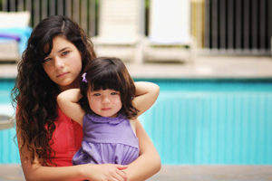 a young adult and child next to a pool.