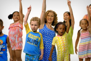 a group of children and one adult with their hands in the air.
