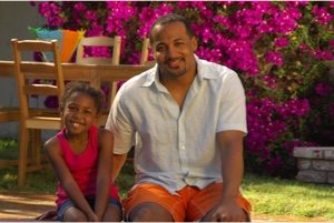 a man and a young girl smiling and sitting next to each other.