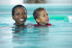 a woman and small child with just their heads above water in a pool.