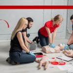 a group of young adults learning CPR.