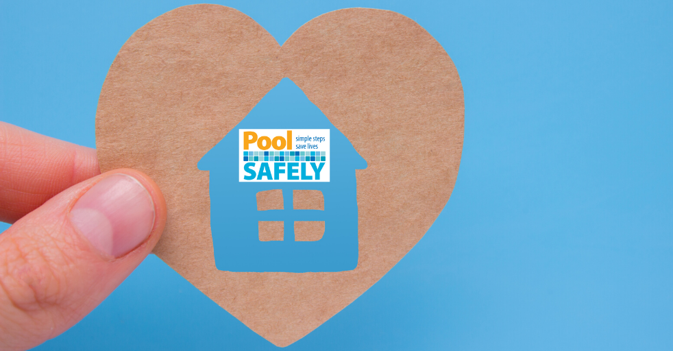 closeup of a person holding a heart shape with a house inside that has the pool safely logo on it.