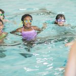 4 kids in a pool learning how to swim