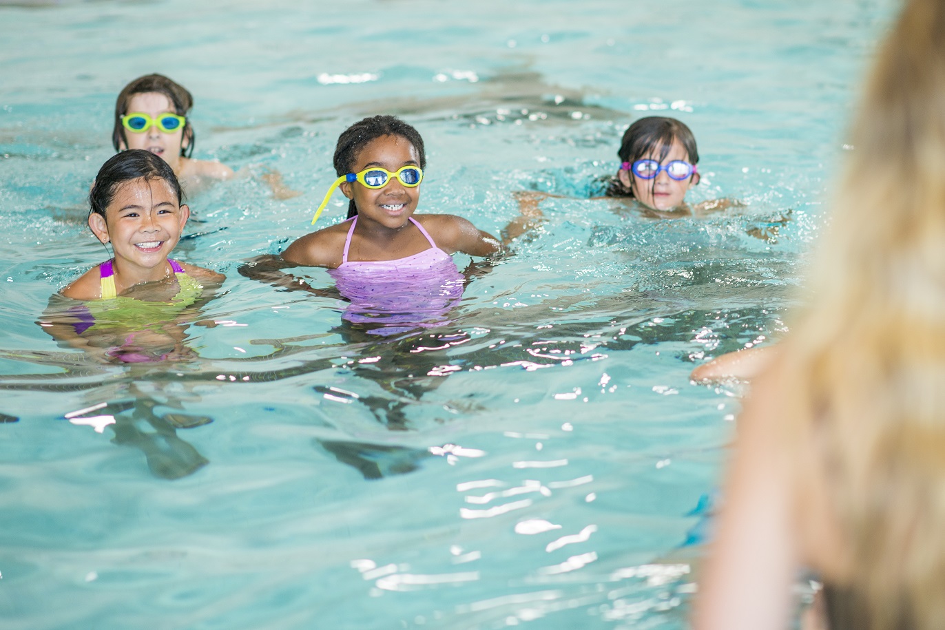 4 kids in a pool learning how to swim