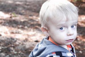 a young kid facing the camera outside