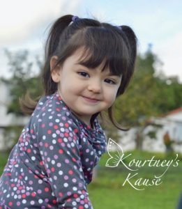 a young girl with pigtails looks to camera with a slight smile.