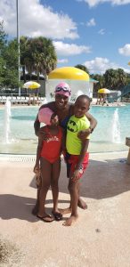 a woman and two younger children at a water park, hugging.