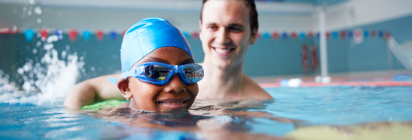 kid swimming in a pool with adult supervision