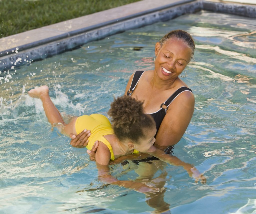 adult teaching kid how to swim